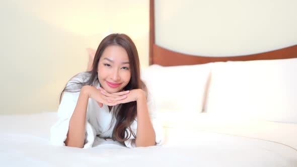 Asian woman relax on bed in bedroom interior alt