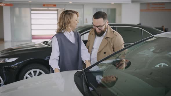 Husband and Wife Choose a New Car in the Showroom of an Official Dealer alt