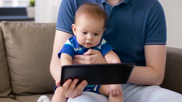 Baby Boy with Father Looking at Tablet Pc at Home  alt