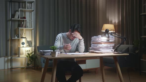 Tired Asian Man Shaking His Head While Working Hard With Documents At Home alt