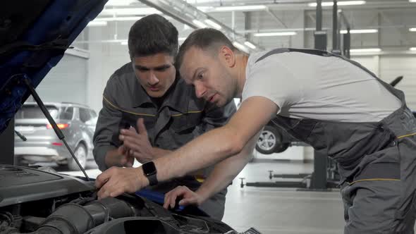 Auto Mechanics Discuss Broken Car at Their Garage Looking Under the Hood