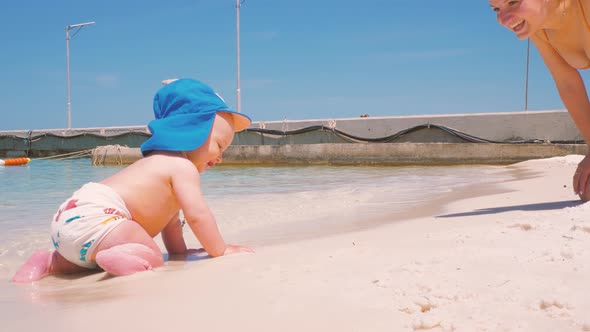 For the First Time, a Child Near the Ocean with His Mother Touches Salt Water  alt