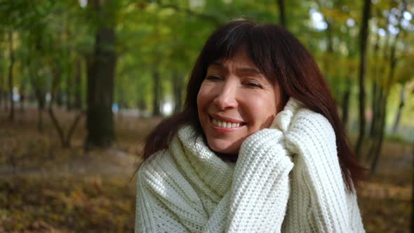 Closeup Portrait of Happy Mature Woman with Toothy Smile Looking at Camera Caressing Face alt
