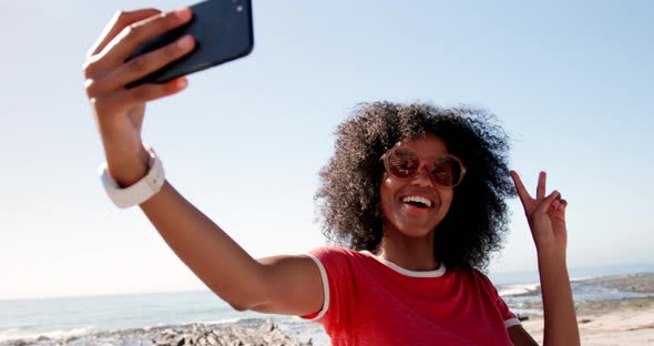 Woman taking selfie with mobile phone on beach in sunshine 4k