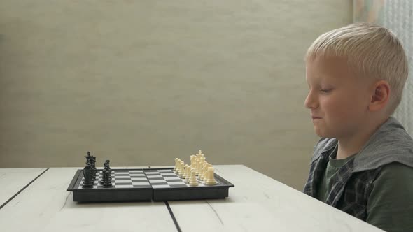 Cute Little Boy Playing Chess at Home
