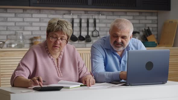 Elderly Spouses are Spending Weekend at Home Woman is Calculating Utility Bills and Her Husband is alt