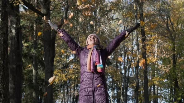 Happy Woman Throwing Dry Autumn Leaves Above Her alt