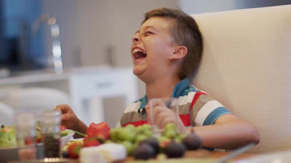 Happy caucasian grandson laughing at table, sitting beside grandfather during family meal alt