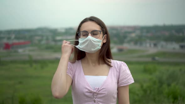A Young Woman with Glasses Takes Off Her Medical Mask and Breathes Freely alt