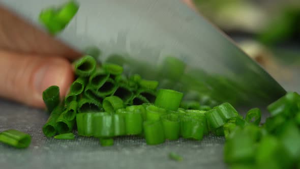 Close Up of Male Chefs Hands Cut Fresh Green Onions with Kitchen Knife alt