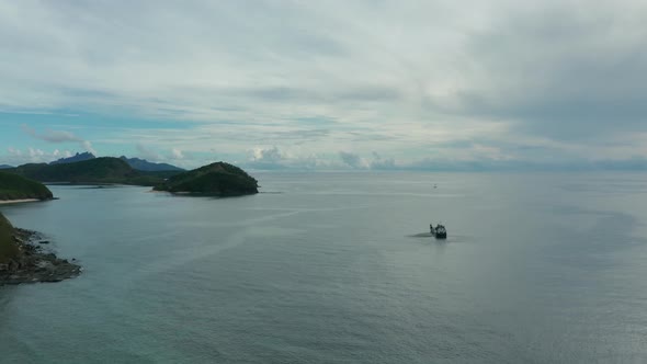 Helicopter hovering above barge waiting for bag to be loaded hanging from cable alt