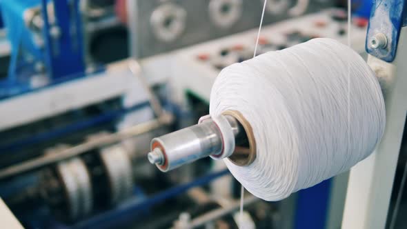 Close Up of a Spool with White Thread Going Through It alt