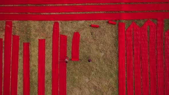Aerial view of a man walking along red long textile stripes, Bangladesh. alt