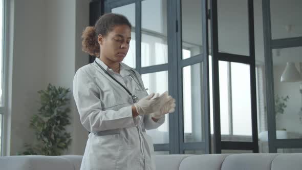 African Female Doctor Putting on Medical Glove alt