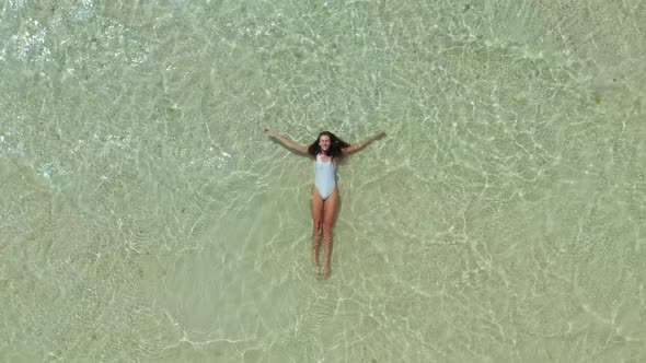View From the Top As a Woman in White Swimsuit Swims in the Ocean alt