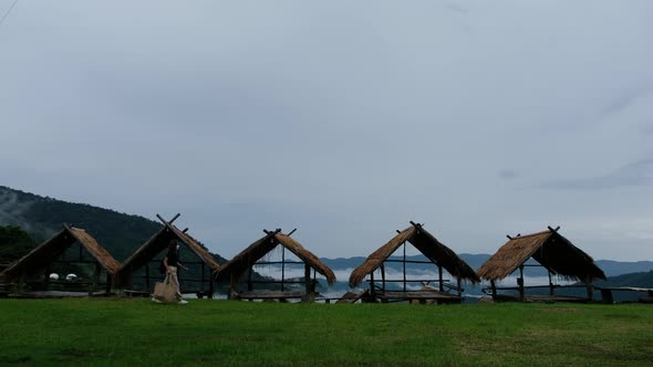 A woman with bags walking pass a local huts in mountain village