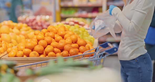 Closeup a Woman Takes Oranges and Puts Them in a Bag alt