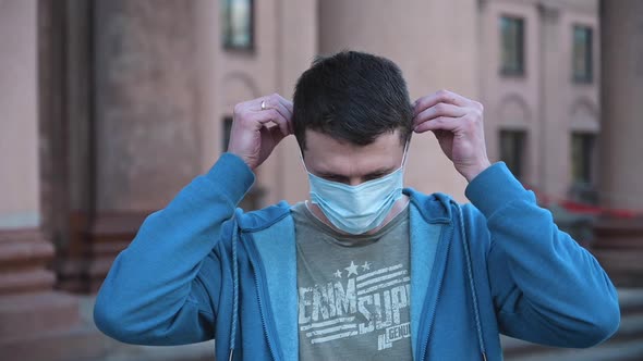 Portrait of Caucasian Man Putting Medical Mask on Face
