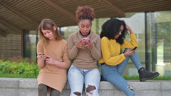 friends are sitting in the park and are bored, flipping through social networks alt