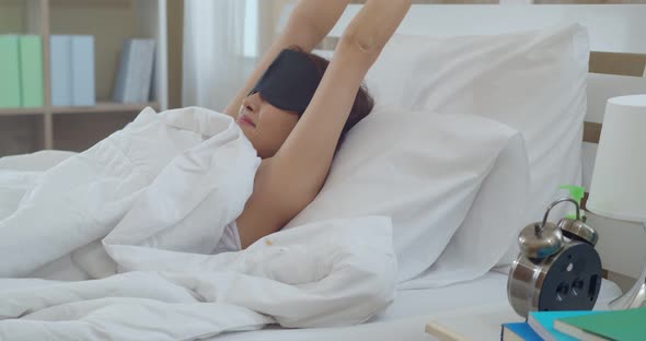 Asian young woman waking and touching alarm clock
