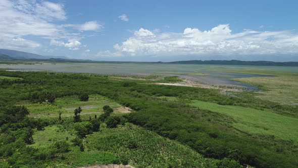 Flying over farmland near a lake surrounded by beautiful mountains and fluffy white clouds, Laguna C alt