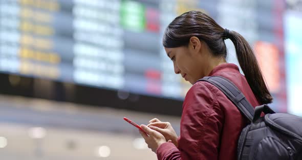 Woman use of mobile phone to check the flight number in the airport alt