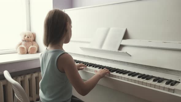 Little Girl Studying To Play the Piano at Home. Preschool Child Having Fun with Learning To Play alt