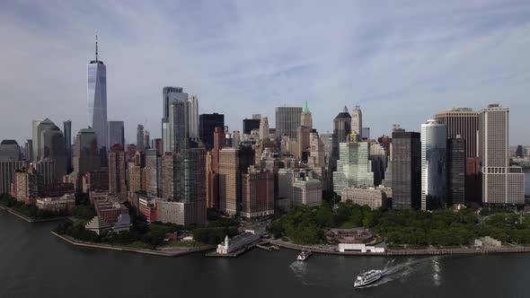 Aerial view of a ferry leaving the lower Manhattan, sunny, summer in NYC, USA - circling, drone shot alt