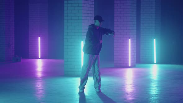 A Steel Man Dances Hiphop Freestyle in a Modern Style in a Hall with Neon Light in Purple Blue alt