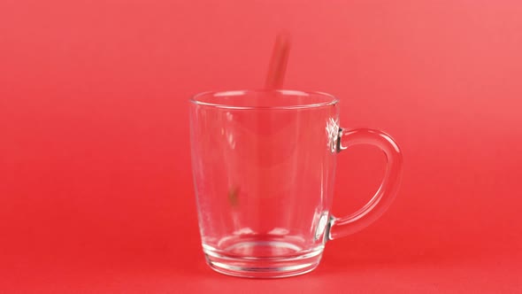 Coffee Beans Quickly Pour, Transparent Glass Cup, Red Background. Energy Concept alt