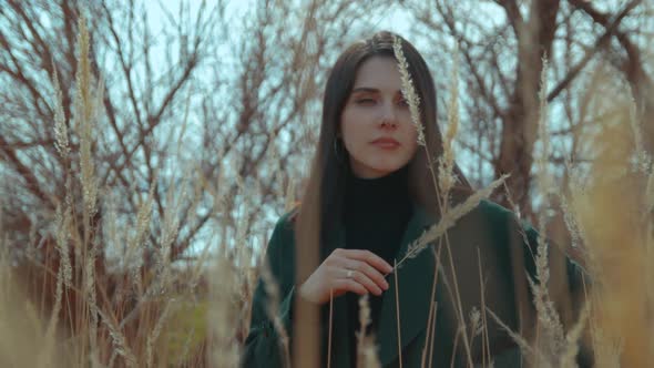 Young Brunette Among the Reeds Touching Her Face By a Straw