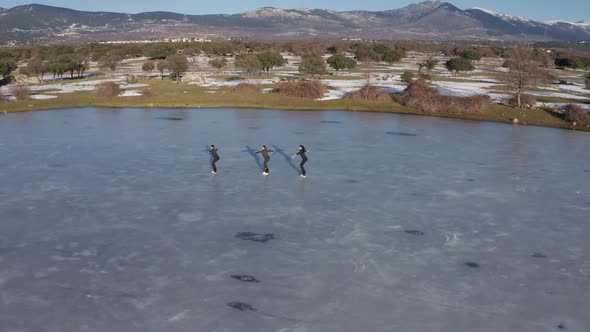 Three young women figure skating on frozen lake alt