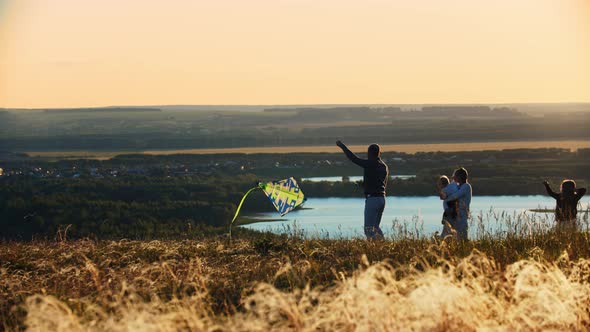 Young Family Playing with Kite on Sunset Wheat Field alt