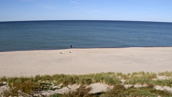 A Woman Runs Along the Sand Along the Bay