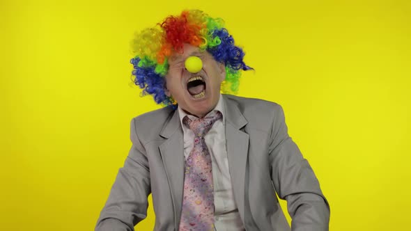 Senior Clown Businessman Entrepreneur Boss Making Silly Faces. Yellow Background alt