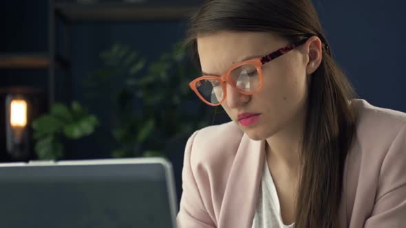 Close Up Portrait of a Beautiful Serious Woman in Glasses Working at a Laptop alt