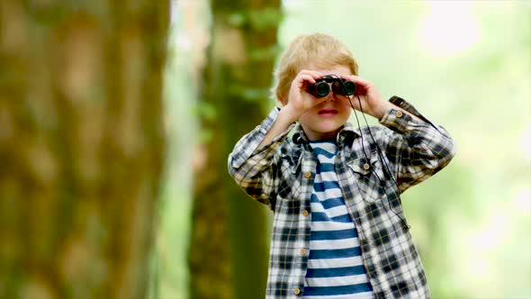Boy Looking Through Binoculars While Hiking In Woods alt