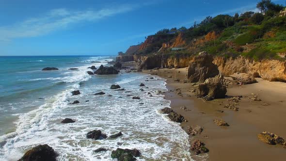 Aerial camera moving over rocks and foaming waves at El Matador Beach Malibu, Califronia, USA alt