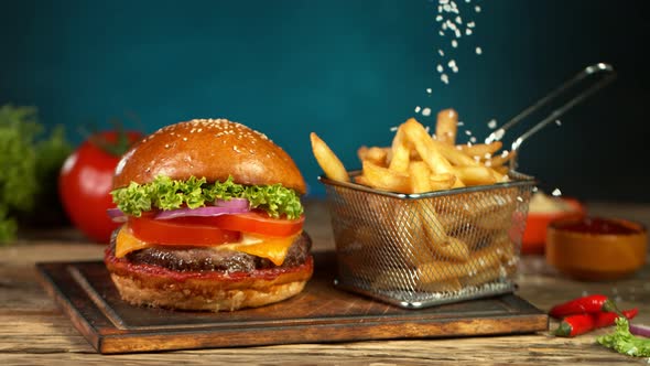 Super Slow Motion Shot of Falling Salt on Fresh Freench Fries Next to the Hamburger at 1000Fps alt