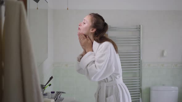 Side View Portrait of Young Slim Woman Washing Face with Clear Water in Bathroom at Home in the alt