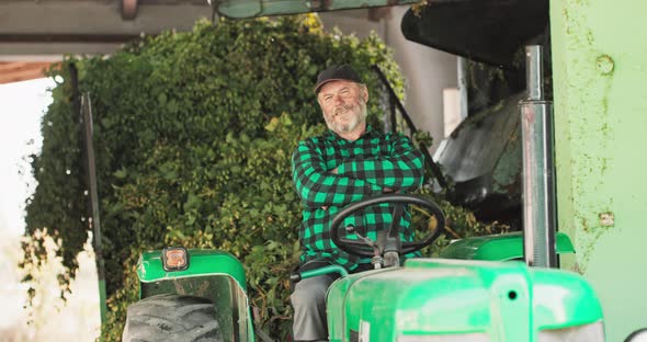 The Friendly Owner of the Plantation Sits on Tractor Andcrosses His Arms Over His Chest alt