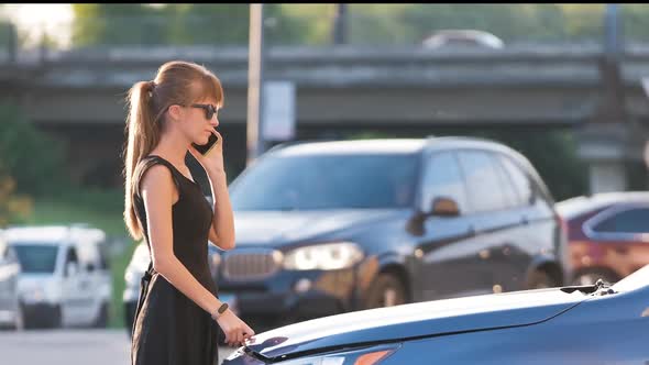 Helpless Woman Standing Near Her Car with Open Bonnet Calling Road Service for Help alt
