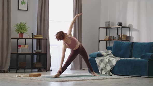 Adult Woman is Performing Yoga Asana at Home Training Alone in Living Room of Modern Apartment alt