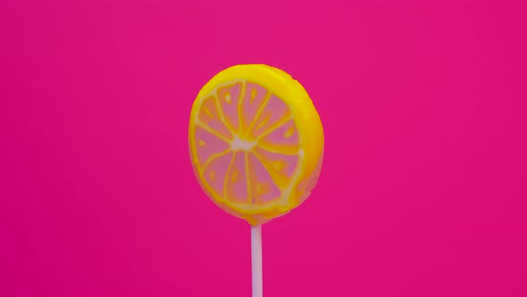 Lollipop Spins On A Stick On A Pink Background, Lemon Candy On A Stick. Caramel Sweetie alt