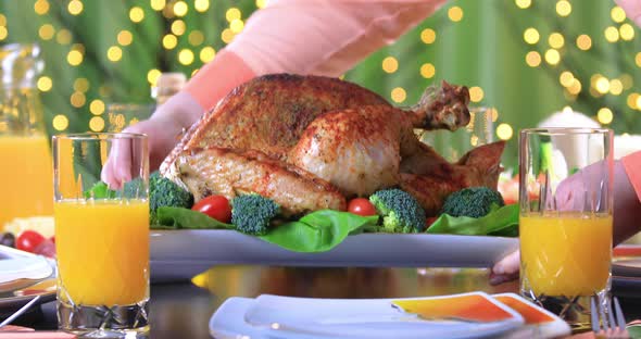 Hands Putting Roasted Turkey on Festive Table Closeup
