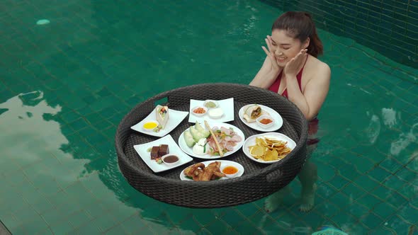 cheerful young woman enjoying with floating food in swimming pool