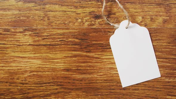 Video of white gift tag with copy space and string on wooden background alt