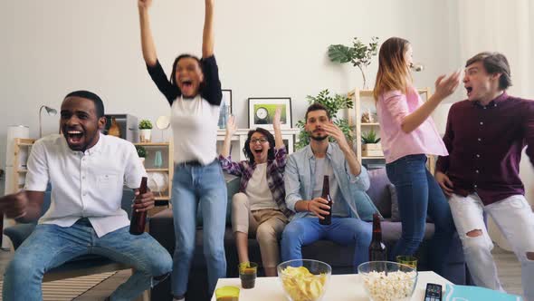 Girls and Guys Are Happy After Watching Sports Game on TV at Home Together alt