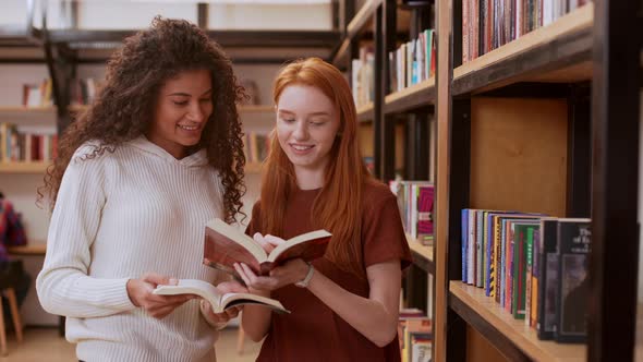 Young Beautiful Girl with Curly Hair and White Sweater Discussing Books with Female Redhead Teenage alt
