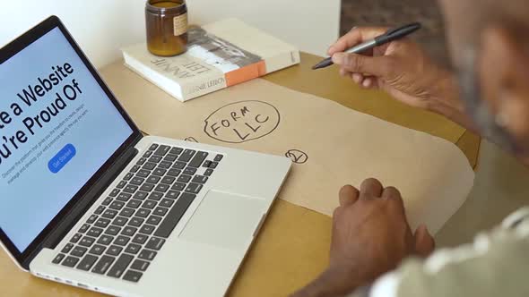 Education Stock Footage 4 K Ultra Hd Clips   A Man Writing On A Paper In Front Of His Laptop alt